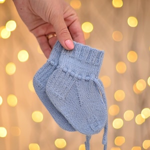 May include: A pair of light blue knitted baby booties with a tie at the top.