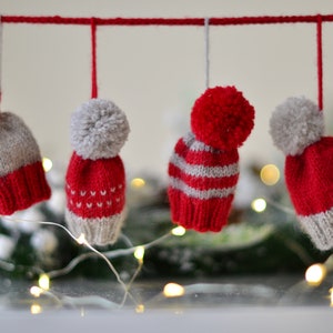 Peut inclure: Quatre bonnets d'hiver en tricot rouge et gris avec des pompons suspendus à une ficelle.