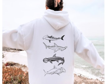 May include: White hoodie with a graphic of four different types of sharks on the back. The sharks are drawn in black and white and are arranged vertically.