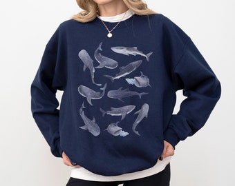 Könnte beinhalten: Ein marineblauer Pullover mit einem grafischen Druck von mehreren Walhaien in Blautönen und Grau.
