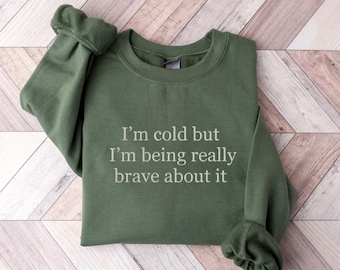 May include: A green sweatshirt with the text "I'm cold but I'm being really brave about it" printed on the front.