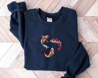 May include: A navy blue sweatshirt with an embroidered design of three orange and white koi fish.