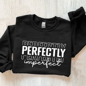 May include: Black sweatshirt with white text that reads "Perfectly Imperfect" in a layered, stylized font.