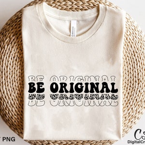 May include: A white t-shirt with the text "BE ORIGINAL" in black letters with a leopard print pattern. The text is in a retro font style.