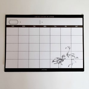 May include: Black and white monthly planner with a flamingo illustration. The planner has a black border and the text "SAIKA MONTHLY PLANNER" and "ZAOMO" are printed on the top and bottom of the planner.