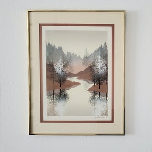 以下が含まれることがあります： 霧のかかった森の風景が描かれた額装されたプリント。川が木々の中を蛇行している。木々は落ち着いた緑色と茶色で、手前に白い先端の木がいくつかある。川は薄い青色で、空は薄い黄色。プリントは右下に「Arthur Snyder」と署名されている。