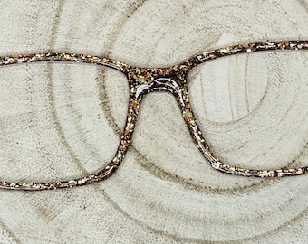 May include: Gold glitter eyeglasses with a square frame.