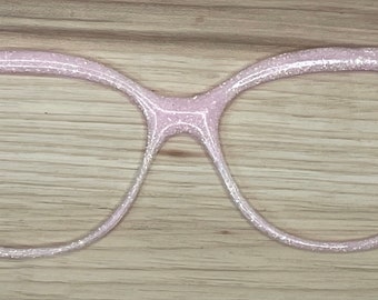 May include: A pair of pink glitter cat eye glasses. The glasses are made of a clear plastic material and have a sparkly finish.