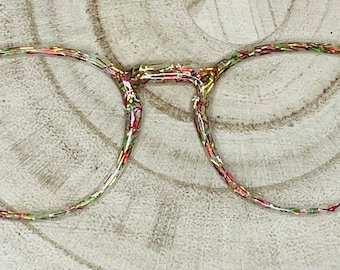 May include: Round eyeglasses with a clear frame and a colorful, speckled pattern. The frame is made of plastic and has a red, yellow, and green speckled pattern.
