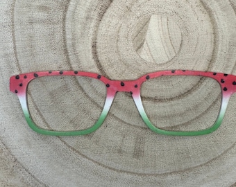 May include: Watermelon-patterned glasses with red and green frames and black seeds. The glasses are made of wood and have a white stripe in the middle of the frame.