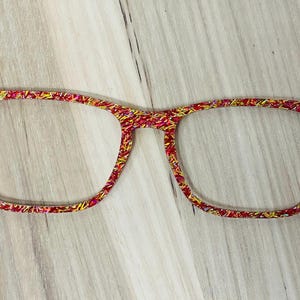 Op de afbeelding: Rode en gouden gepatroneerde bril met een heldere lens.