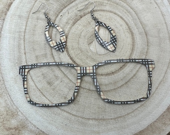 May include: A pair of black and white plaid eyeglasses with a matching pair of earrings. The earrings are oval shaped with a small hole in the center.
