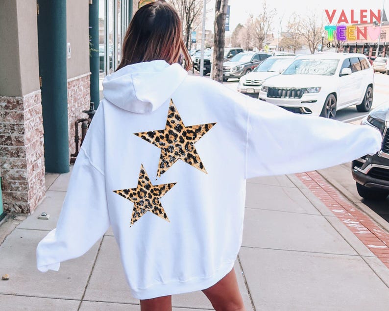 May include: White hoodie with a hood and long sleeves. The back of the hoodie features two leopard print stars. The hoodie is a casual style, suitable for everyday wear. The brand name "VALENTEEN" is visible in the background.