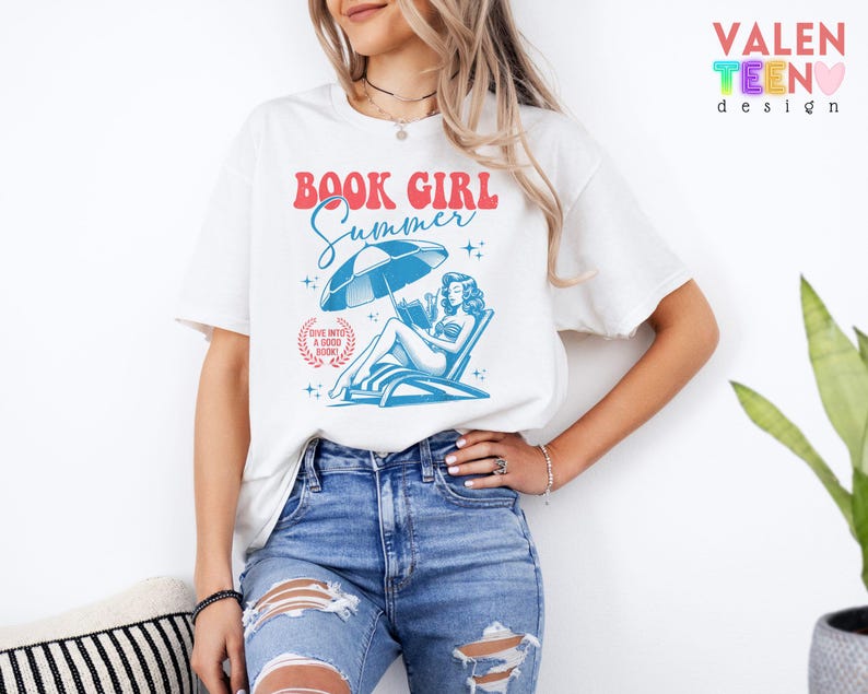 May include: White t-shirt with the text "BOOK GIRL Summer" in red and blue. The graphic features a woman reading under a beach umbrella. The shirt also has the text "Dive into a good book!" in a circular design.