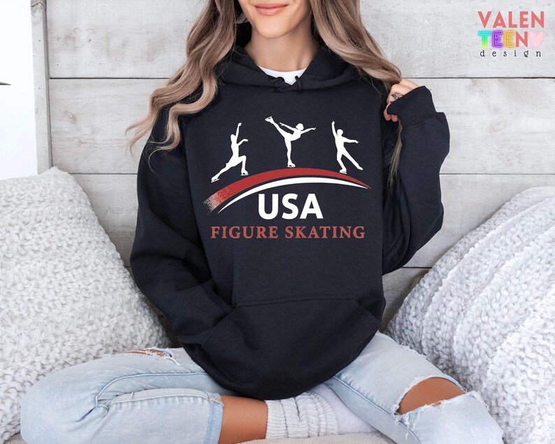 May include: Black hooded sweatshirt with a white graphic of three figure skaters above the text "USA FIGURE SKATING" in red and white. The sweatshirt has a front pocket and a drawstring hood.