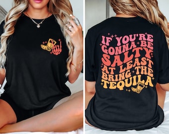 Może przedstawiać: Czarny T-shirt z grafiką kieliszka do shotów i szkieletu dłoni z przodu oraz tekstem "If you're gonna be salty at least bring the tequila" z tyłu.