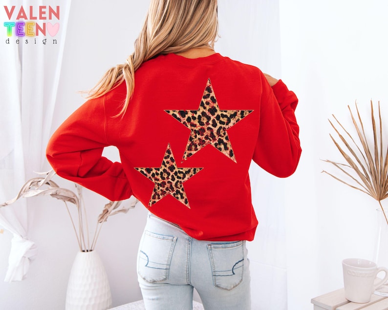 May include: A red sweatshirt with two leopard print star designs on the back. The sweatshirt has long sleeves and a crew neck. The text "VALEN TEEN design" is visible in the upper left corner.