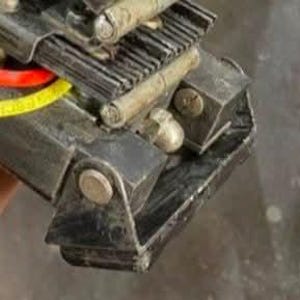 May include: Close-up of a black metal tool with a silver metal tip and a black plastic base. The tool has a series of gears and a small metal lever.