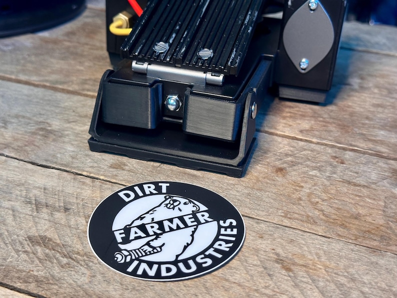 May include: A black and white sticker with the text "Dirt Farmer Industries" and a white polar bear graphic. The sticker is on a wooden surface.