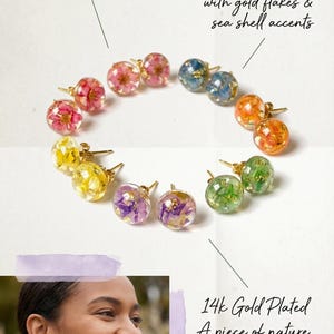 May include: Handmade stud earrings with real dried flowers set in clear resin, with gold flakes and sea shell details. The earrings are on 14k gold-plated posts. The text reads "Staircase Atelier".