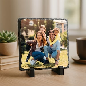May include: A square slate photo tile with a family portrait, supported by a black stand. The image shows a smiling family of four in a natural outdoor setting. The tile has a rough, textured edge and is displayed on a wooden surface.