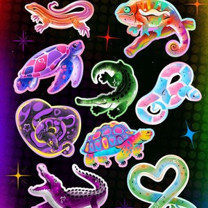 May include: A collection of holographic stickers featuring various reptiles and amphibians in vibrant colors. The set includes a lizard, chameleon, turtle, alligator, snake, and a heart-shaped snake design. The text reads Pride Reptile Stickers!