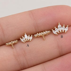 May include: Four gold-toned crown-shaped jewelry components featuring marquise-cut clear stones. Each piece has a small threaded post on the back. The items are labeled with the letters A and B to distinguish between the different sizes and designs.