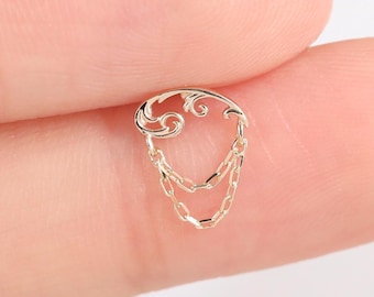 May include: A small gold-toned metal earring featuring a decorative curved top piece with an openwork swirl design. Two delicate, thin gold-toned chains hang from the base of the top piece, creating a layered, dangling effect on this jewelry item.