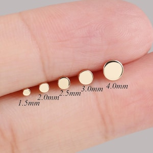 Peut inclure: Ensemble de six boucles d'oreilles dorées de différentes tailles, allant de 1,5 mm à 4,0 mm de diamètre. Les boucles d'oreilles sont présentées sur un doigt, mettant en valeur leurs tailles variées. Fond neutre.