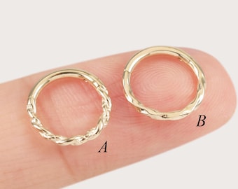 May include: Two gold-toned hoop rings are displayed. Ring A features a twisted rope-like texture, while ring B has a smooth, slightly undulating surface. Both circular rings are positioned side by side, clearly labeled with the letters A and B.