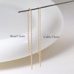 May include: Gold-tone dangle earrings. One pair has a bead chain, the other a cable chain. Each earring features a long, slender bar pendant. The earrings are shown against a white backdrop with the text "Bead Chain" and "Cable Chain".