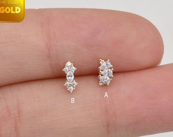 Könnte beinhalten: Zwei goldene Ohrringe mit klaren Edelsteinen werden gezeigt. Ein Ohrring, mit der Bezeichnung "B", hat einen zentralen Stein im Marquise-Schliff mit kleineren Steinen darüber und darunter. Der andere, mit der Bezeichnung "A", hat drei tropfenförmige Steine.