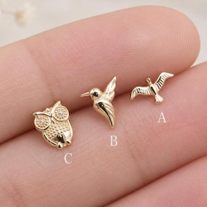 May include: Three gold-toned metal stud earrings shaped like animals. Item A is a bird in flight, item B is a hummingbird, and item C is an owl with two small clear stones for eyes. Each piece is labeled with its corresponding letter A, B, or C.