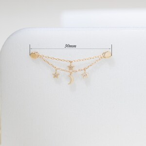 May include: A gold-toned double chain earring connector featuring two small star charms, one crescent moon charm, and two circular end posts. The piece measures 30mm in total length as indicated by the measurement lines visible in the image.