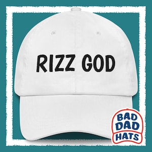 May include: White baseball cap with black embroidered text that reads "Rizz God". The cap has a curved brim and a Bad Dad Hats logo on the side.