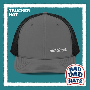 May include: Gray trucker hat with a black mesh back. The hat has white embroidery that says "old timer".