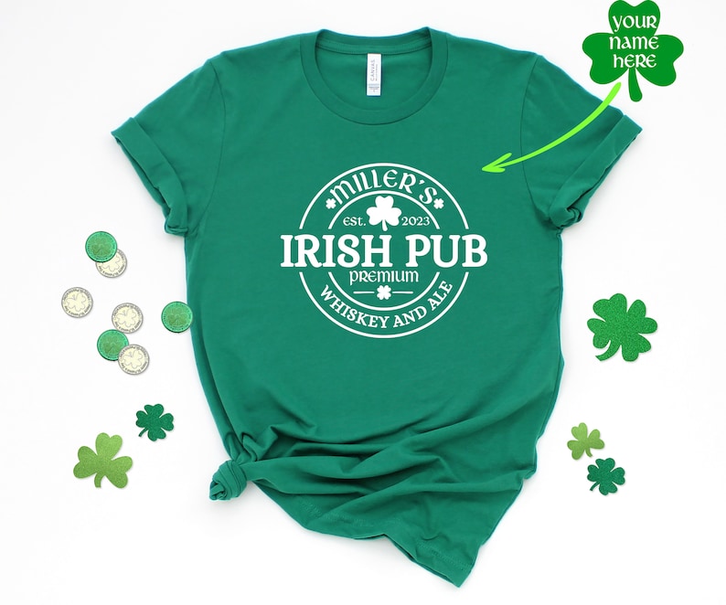 May include: Green t-shirt with a white circle design that says "Miller's Irish Pub est. 2023 Premium Whiskey and Ale".