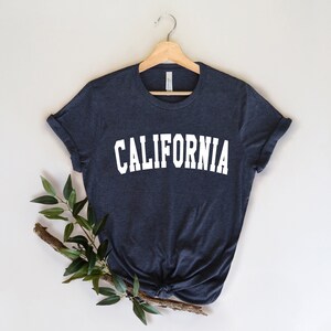 K&ouml;nnte beinhalten: Ein dunkelblaues T-Shirt mit dem Wort "CALIFORNIA" in wei&szlig; auf der Vorderseite.