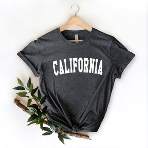 K&ouml;nnte beinhalten: Ein dunkelgraues T-Shirt mit dem Wort "CALIFORNIA" in wei&szlig; auf der Vorderseite.