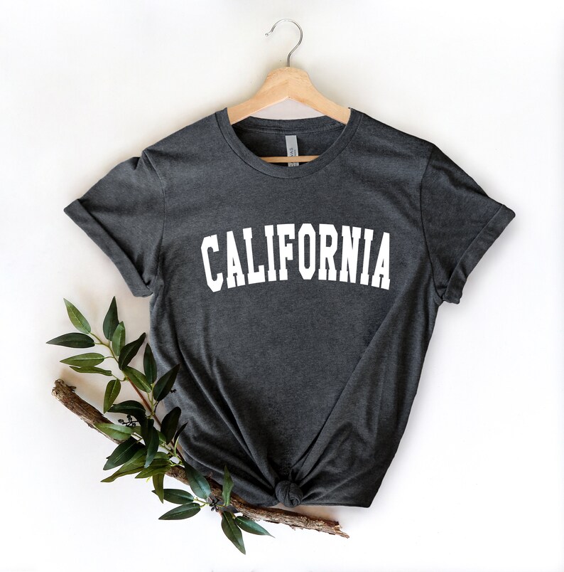 K&ouml;nnte beinhalten: Ein dunkelgraues T-Shirt mit dem Wort "CALIFORNIA" in wei&szlig; auf der Vorderseite.