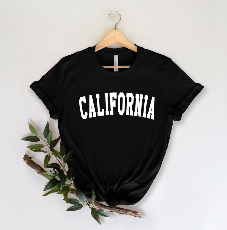 K&ouml;nnte beinhalten: Schwarzes T-Shirt mit wei&szlig;em Text, der "CALIFORNIA" in einer College-Schriftart lautet.