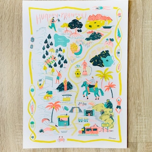 May include: A colorful illustrated map print featuring the text "Hua Hin & Pranburi" in pink. The map includes various illustrations of people, trees, and buildings, with a yellow border and a wooden background.