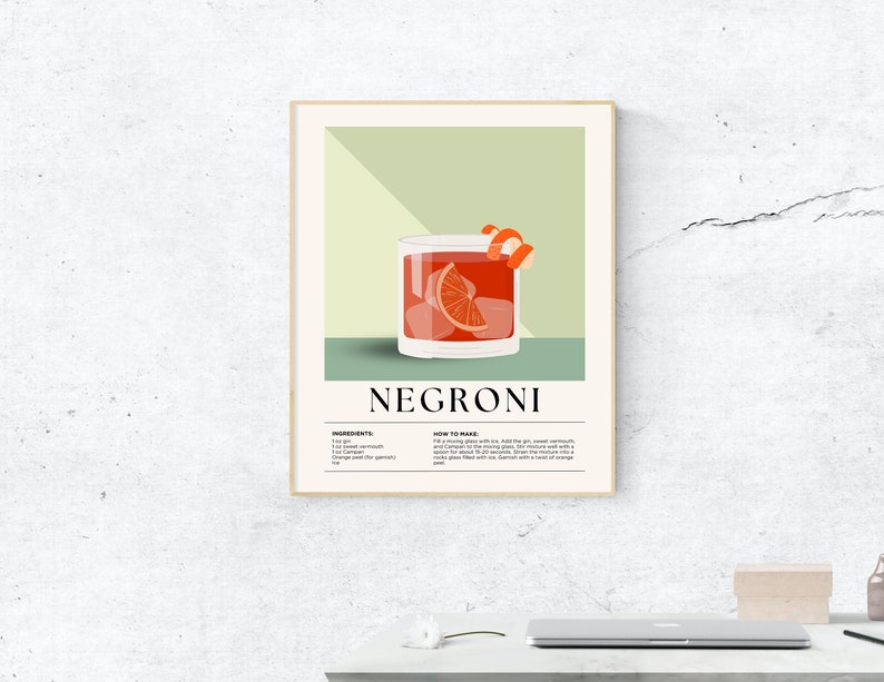 May include: A framed art print featuring a Negroni cocktail illustration. The drink is in a rocks glass with ice, an orange slice, and a twist. The print includes the drink's name, ingredients, and instructions.