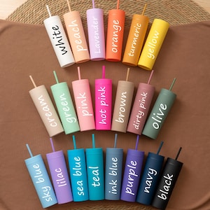 May include: A collection of twenty-one cylindrical tumblers with matching straws, each featuring a matte finish in a distinct colour. The tumblers are labelled with white text identifying the colours: white, peach, lavender, orange, turmeric, yellow, cream, green, pink, hot pink, brown, dirty pink, olive, sky blue, lilac, sea blue, teal, ink blue, purple, navy, and black.