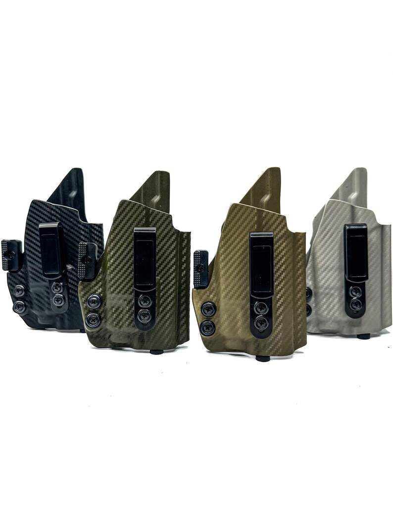 Puede incluir: Cuatro fundas de diferentes colores para llevar ocultas. Las fundas est&aacute;n hechas de un material de fibra de carbono y tienen un clip negro. Las fundas est&aacute;n dispuestas en una fila de izquierda a derecha, con la funda negra a la izquierda, la funda verde en el medio y la funda gris a la derecha.