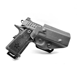 May include: A black handgun with a textured grip and a black holster. The holster has a clip on the bottom and a screw on the side.