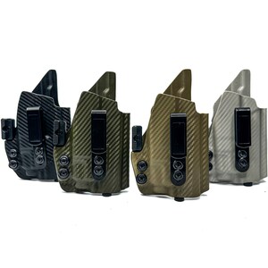 May include: Four different coloured holsters for concealed carry. The holsters are made of a carbon fibre material and have a black clip. The holsters are in a row from left to right: black, green, brown, and grey.