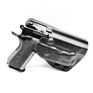 May include: A black polymer holster with a black handgun inside. The holster has a textured surface and is secured with screws.