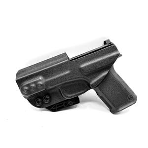 Puede incluir: Una funda de pol&iacute;mero negra con una pistola negra en su interior. La funda tiene una superficie texturizada y un clip para cintur&oacute;n.