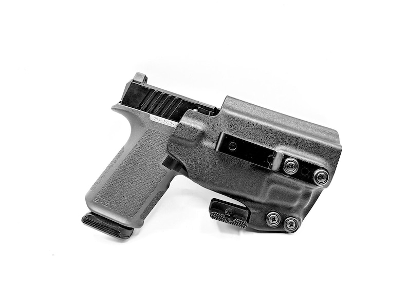 May include: A black handgun with a black holster. The holster has a belt clip and multiple screws.